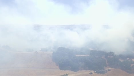 Trucks-sit-at-the-bottom-of-a-smoky-and-fire-filled-ridge