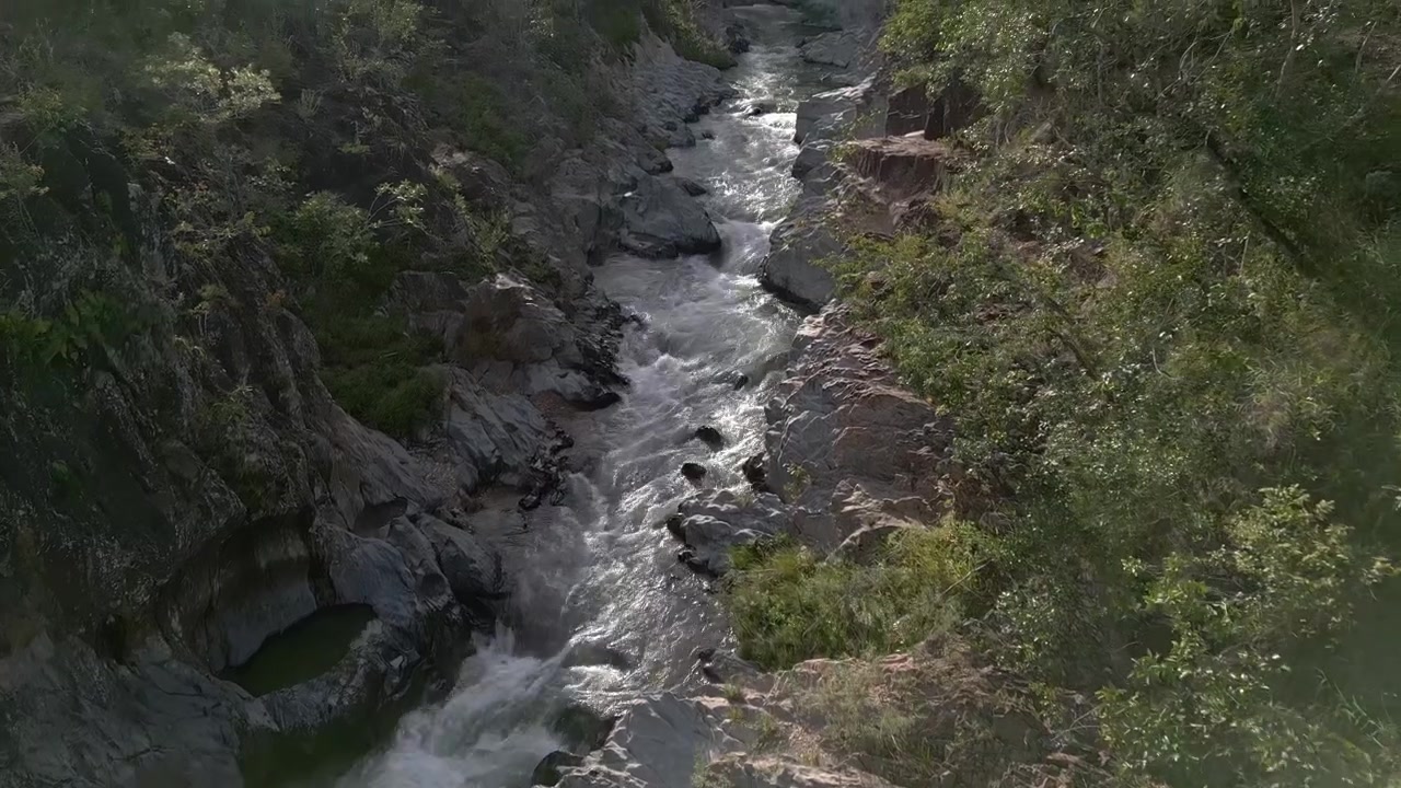 Rapide del fiume São Miguel che scorrono attraverso un canyon di quarzite nella Serra do Segredo, Chapada dos Veadeiros, Goiás, Brasile, delimitato da foresta a galleria e vegetazione endemica del Cerrado, con un'inquadratura che si inclina in avanti verso il basso