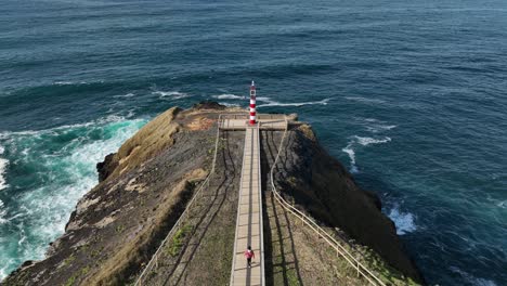 fenais da ajuda lighthouse on rocky promontory, sao miguel, aerial pullback