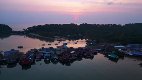 bang bao pier close up, traditional fishing stilt houses reflecting on calm sea at sunset in koh chang, thailand. gorgeous aerial view flight static tripod hovering drone