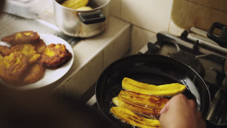 mujer friendo plátanos maduros en una sartén con aceite