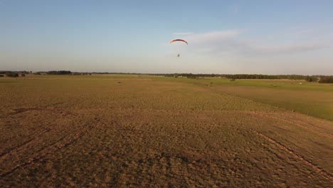 Rear-view-of-motorized-paraglider-takeoff-over-field,-Argentina