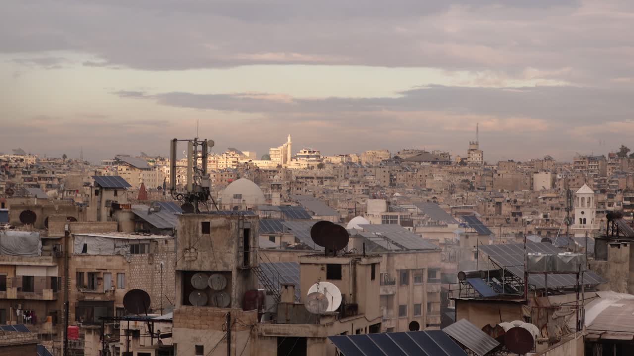 Vista panoramica dello skyline di Aleppo, Siria, al tramonto. Paesaggio urbano storico con cupole, minareti e architettura urbana tradizionale sotto un caldo cielo serale.