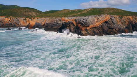 powerful swell hitting rocky coast with splashes rolling white foam drone view.