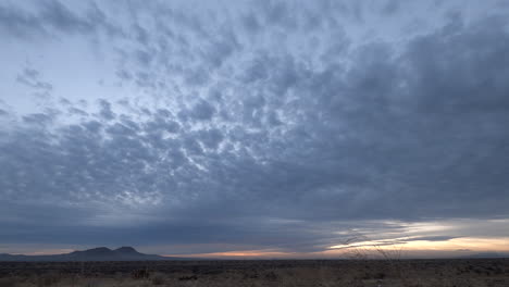 Fiery-red-sunrise-lights-up-thick-clouds-and-fades-in-Mojave-Desert,-Timelapse