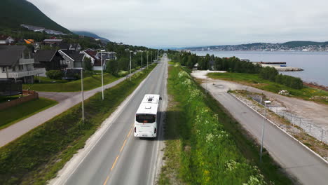 Transporte-En-Autobús-En-Tromso-Por-Una-Carretera-Panorámica-Junto-Al-Fiordo,-Seguimiento-Aéreo.