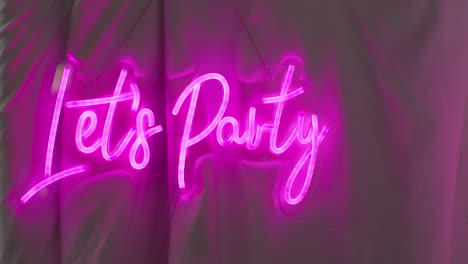 close up of photo booth with neon "let's party" sign hanging outside