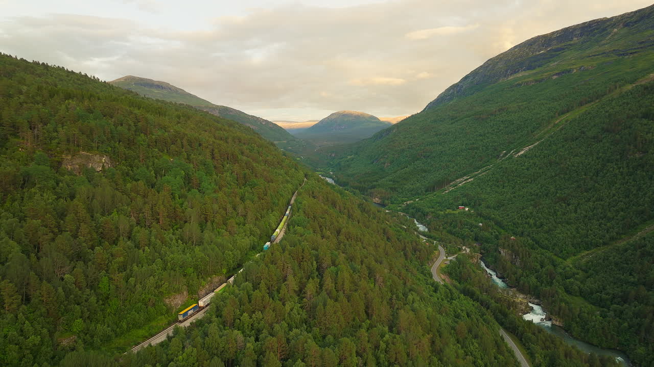 vista de retroceso de un avión no tripulado de un tren de carga que pasa por el valle de romsdalen, noruega
