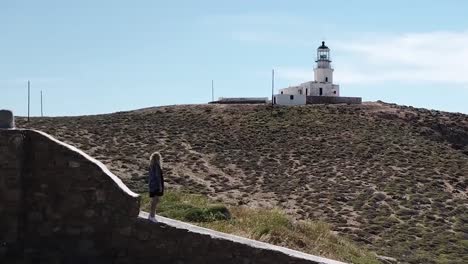 dron aéreo sobre una mujer parada frente al paralaje del faro