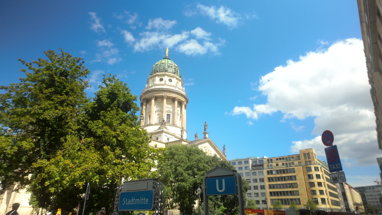 View of Berlin’s Gendarmenmarkt with cathedral and surrounding buildings under clear blue sky