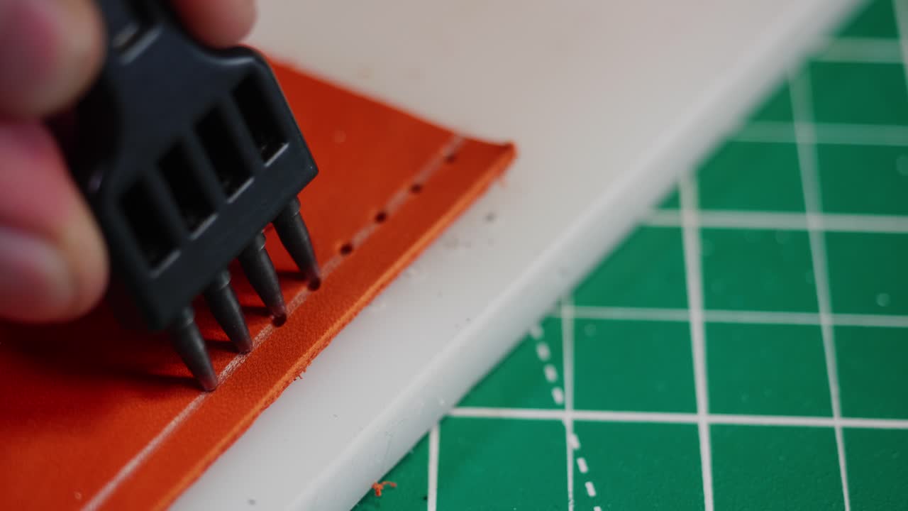 Un conciatore misura e taglia la pelle con attenzione. Il processo include l'uso di strumenti per marcare e creare linee precise sul materiale. Questo avviene in un ambiente di laboratorio dove la precisione è fondamentale.