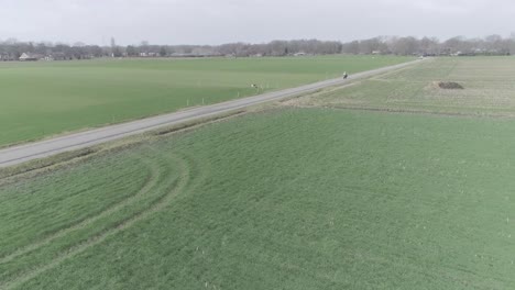 drone shot of motorcyclist driving between farm fields