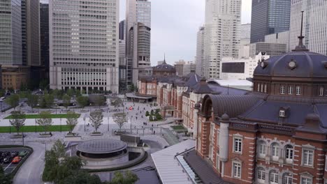 High-above-aerial-view-out-on-famous-Tokyo-Station-at-sunset-with-commuters-moving-around-and-skyscrapers-in-backdrop
