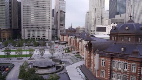 high above aerial view out on famous tokyo station at sunset with commuters moving around and skyscrapers in backdrop