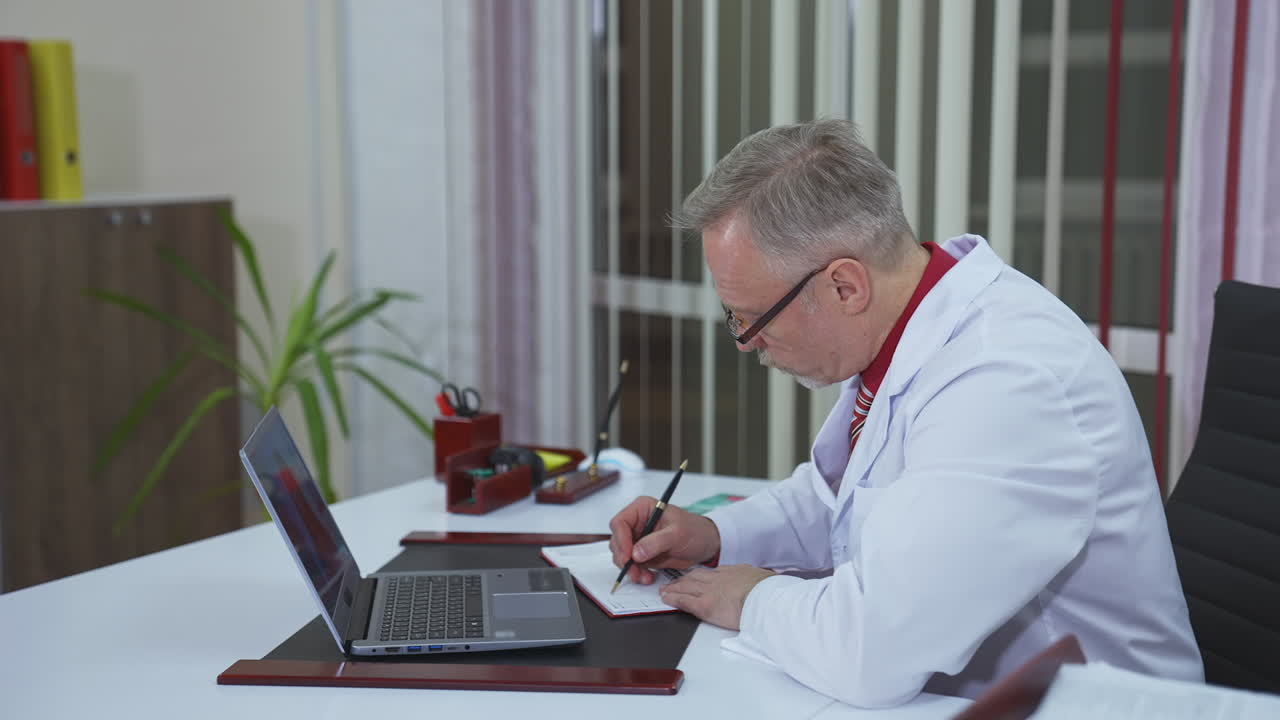 Doctor chatting with patients online, using laptop at his workplace. Telemedicine concept
