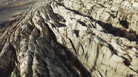 Aerial-landscape-view-rising-through-clouds,-over-the-textured-ice-surface-of-an-icelandic-glacier