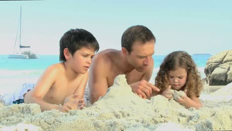 father and his childs building a sand castle