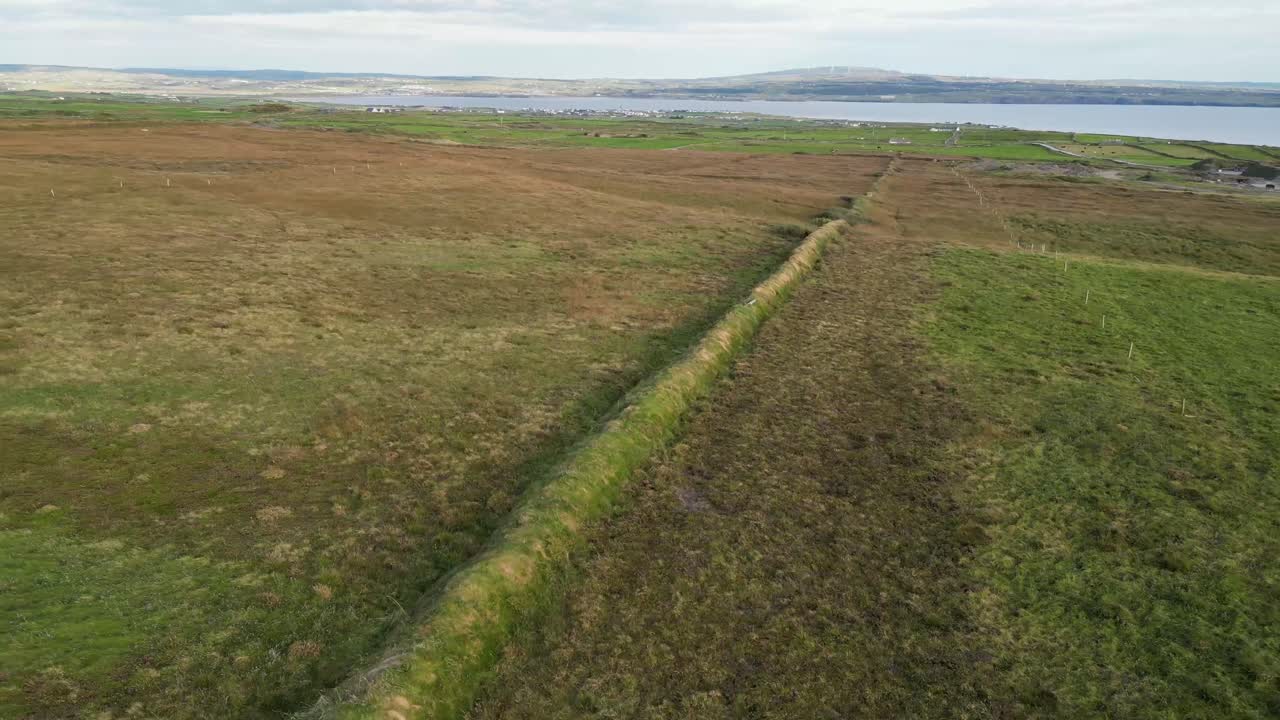 дрон, летящий назад, показывает скалы мохера на закате, в то время как туристы движутся вдоль скал