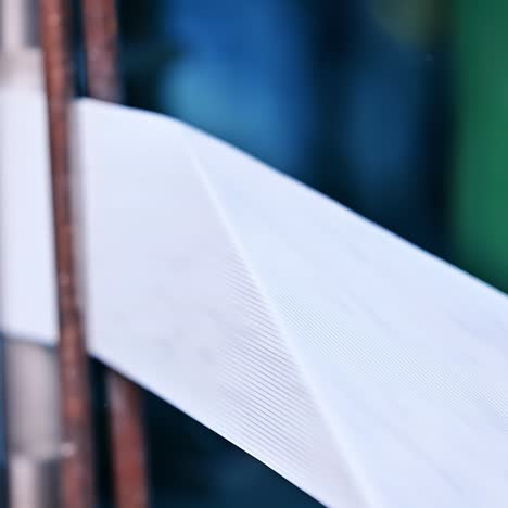 diaper production enterprise. manufacture of durable diaper fasteners from a roll of white ribbon in blur. white band running between the steel rollers close up