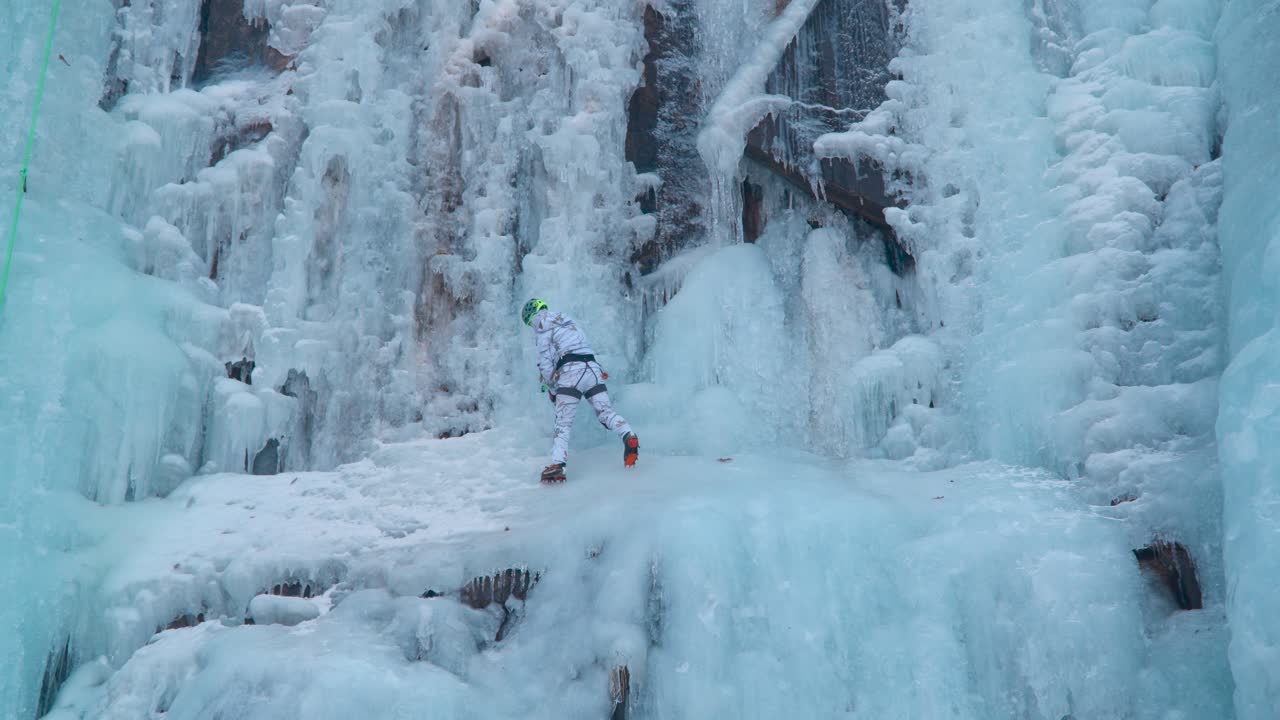 Ice Climber Climbing a Frozen Icy Cliff Cascade Using Two Axes - slow motion