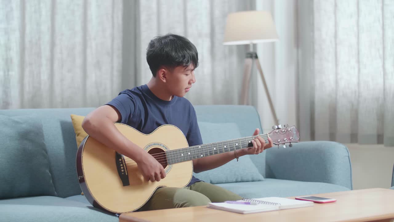집에서 어쿠스틱 기타를 연주하는 십대