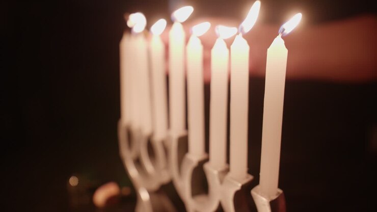 Hand Lighting White Candles on a Menorah for Hanukkah Celebration