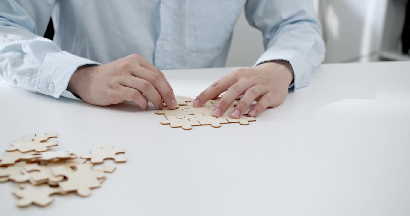 Une personne concentrée assemblant un puzzle en bois pièce par pièce, améliorant la concentration et la pleine conscience
