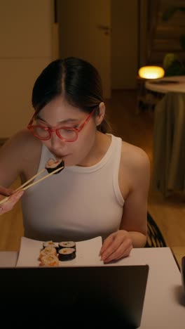 woman eating sushi while working from home