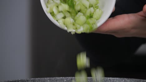 pouring from bowl fresh and healthy green vegetables into pan