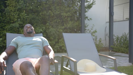 relaxing on lounge chair in backyard, man enjoying sunny day outdoors