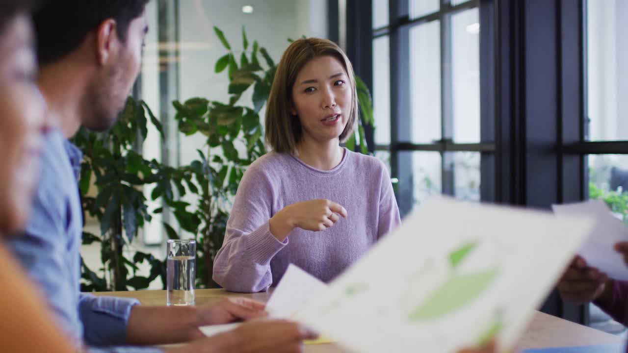 diversas personas de negocios sentadas usando computadoras portátiles pasando por el papeleo en la oficina