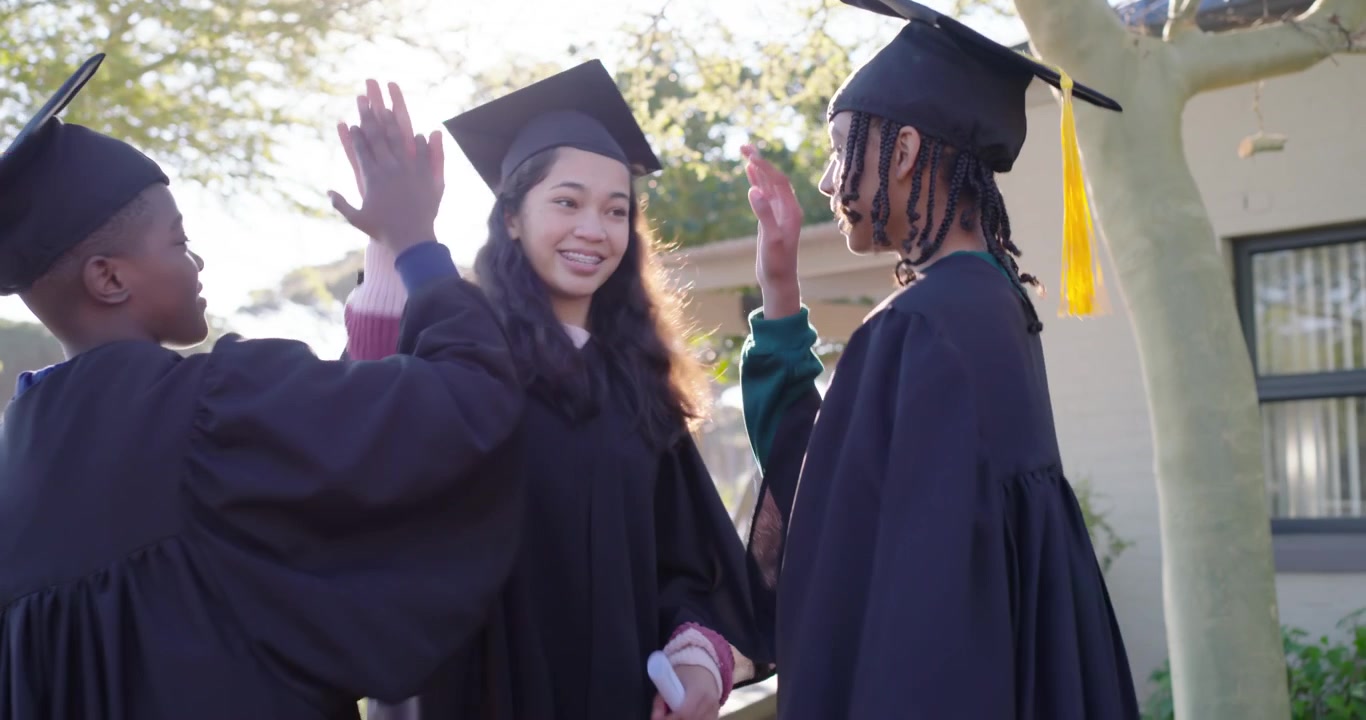 African American graduates in regalia raising smartphone taking selfie, rejoicing, sharing diplomas