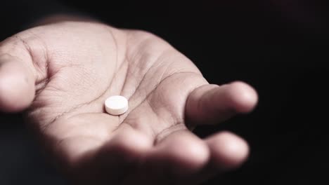 hand holding a white pill