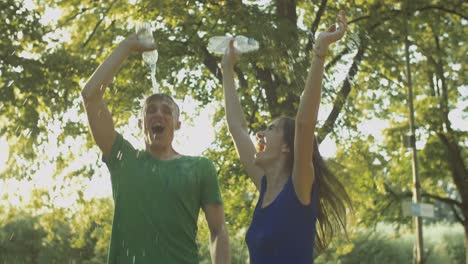 una pareja de corredores emocionados derramando agua sobre sí mismos