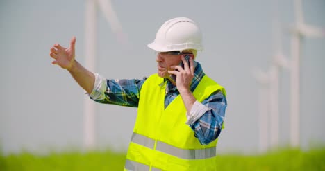 Wütender-Ingenieur,-Der-Am-Handy-Gegen-Windmühlenfarm-Spricht-3