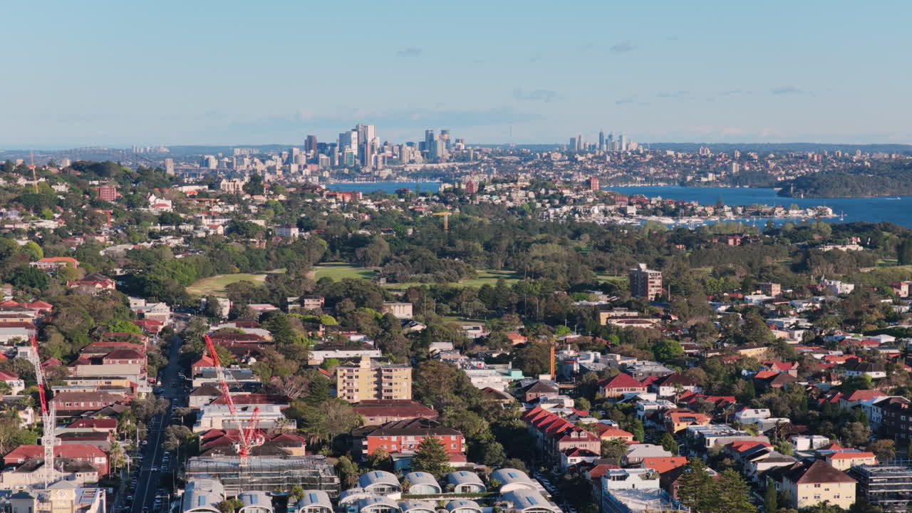 Un'immagine aerea con teleobiettivo che mostra gru e nuove costruzioni nel vivace mercato immobiliare di Bondi Beach, con le pittoresche colline circostanti e l'iconico skyline di Sydney, in Australia, e il porto sullo sfondo