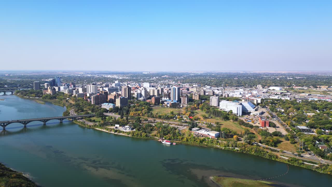 Slow forward aerial focusing on Saskatoon downtown, river and bridges in fall