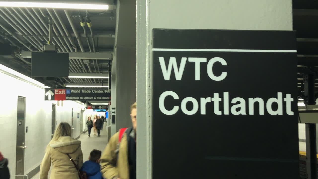 The World Trade Center Cortlandt Street subway station New York City.Camera pans across WTC Cortlandt sign on subway column with commuters walking behind it.