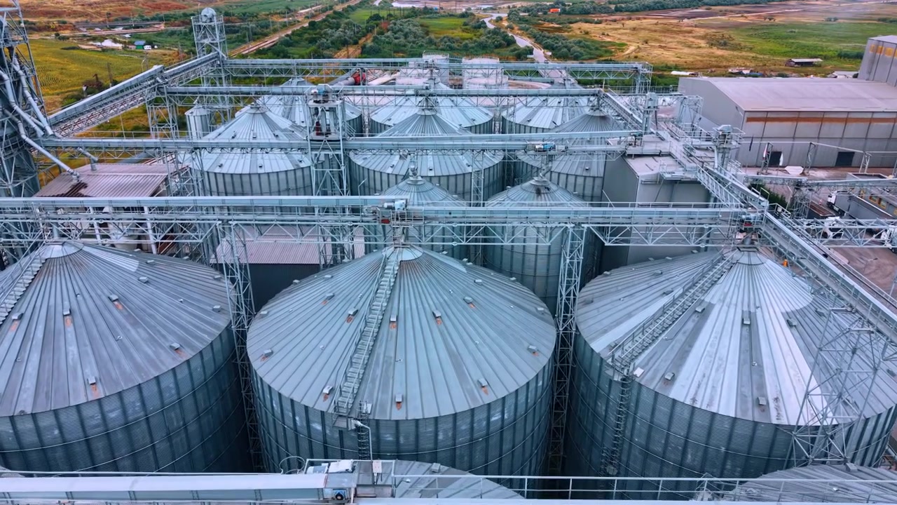 Instalação de armazenamento de grãos com silos em uma área rural durante o dia. Aqui, grandes silos são vistos em uma instalação de armazenamento de grãos em uma área rural.