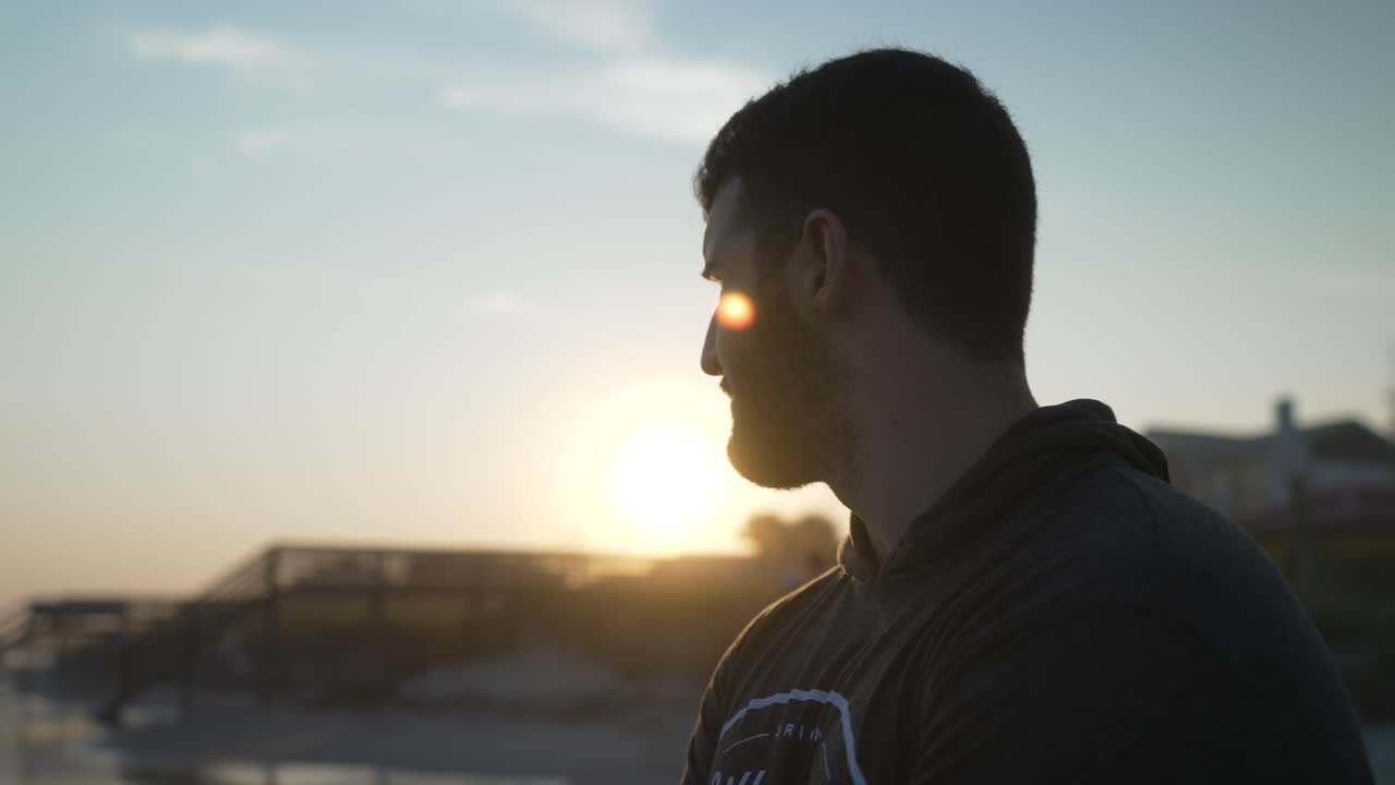 silueta de hombre joven mirando la puesta de sol en folly beach, carolina del sur