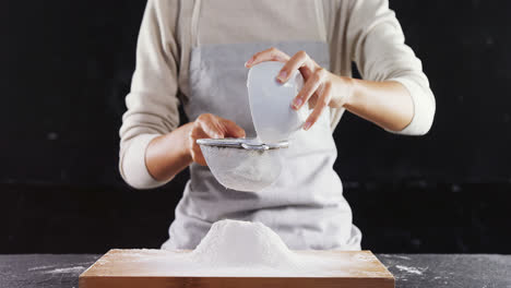 Woman-sieving-flour-from-the-bowl-on-the-wooden-board-4k