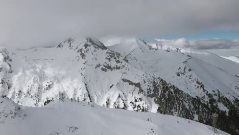 panning slowmotion panoramic drone shot with skiers and snowboarders along the mountainridge