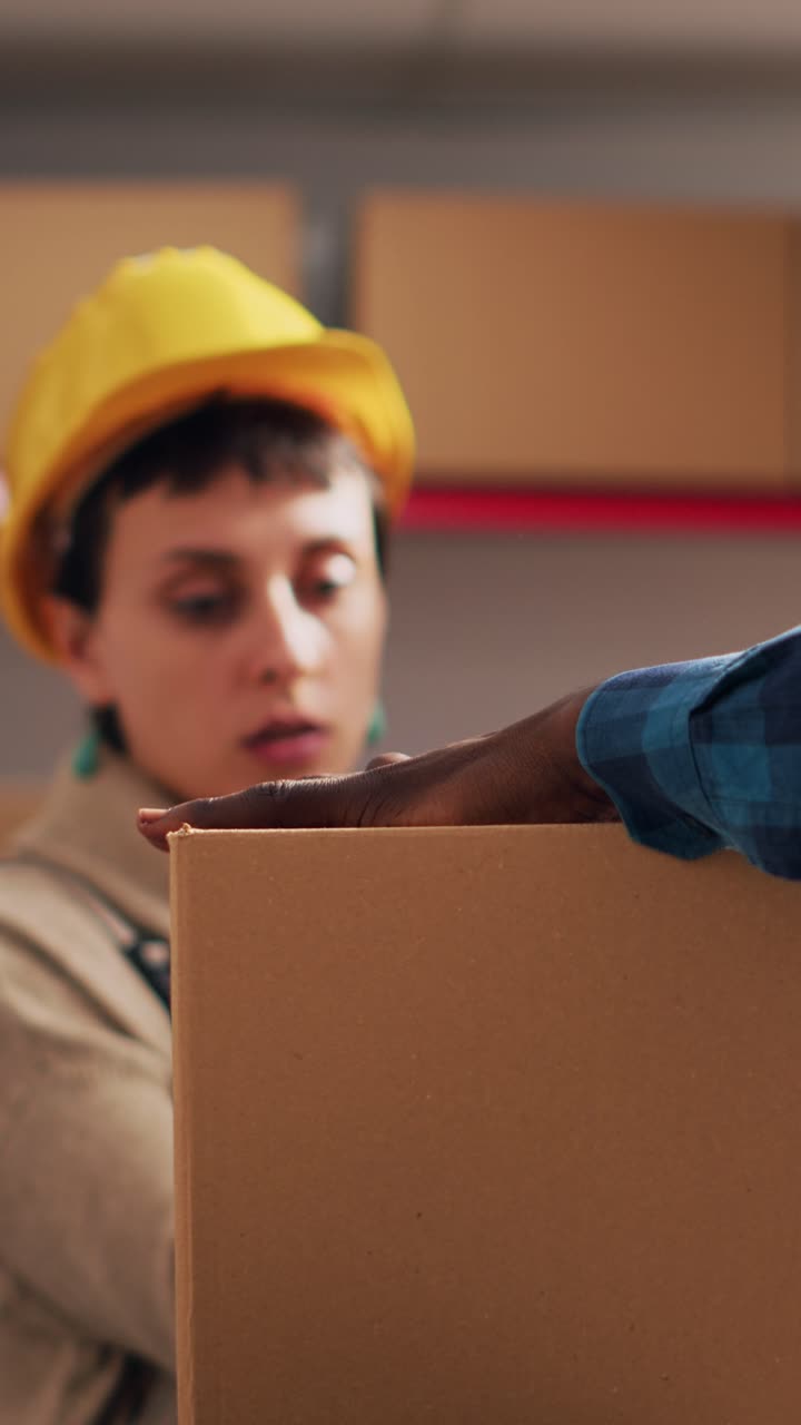 Vertical video: African american man putting adhesive tape on boxes