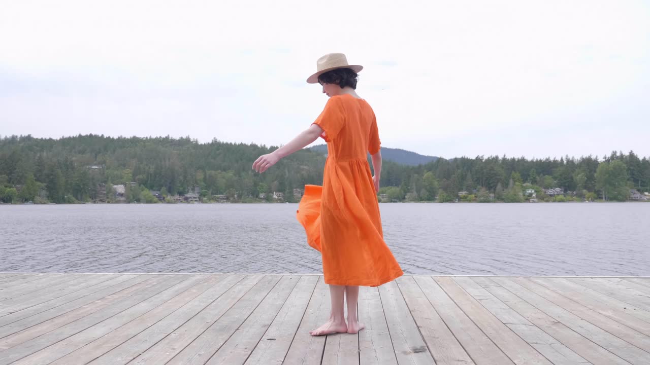 카메라 앞에서 춤을 추는 호숫가 패션 촬영의 젊은 여성