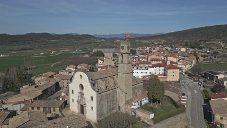 vista aérea orbital de un pequeño pueblo catalán con una torre del reloj con una bandera pro-independencia