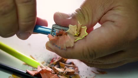 Imágenes-De-Manos-Afilando-Lentamente-Un-Lápiz-Y-Algunos-Lápices-De-Colores-Con-Un-Sacapuntas-De-Cuña