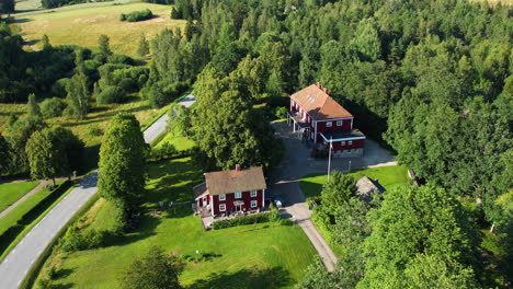 aerial shot of rural sweden featuring red houses surrounded by lush trees and roads