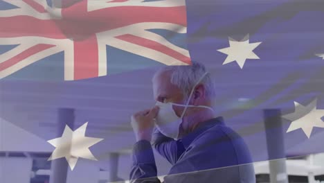 animation of flag of australia waving over man wearing face mask during covid 19 pandemic