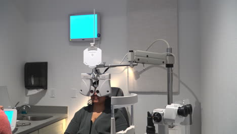 prescription lens testing using phoropter - patient undergoing eye examination in optometrist clinic. - wide shot