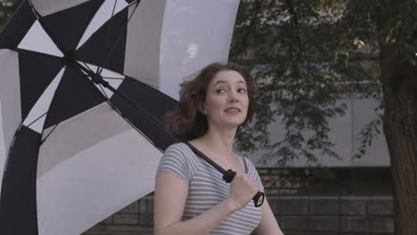 millennial female walks through a college campus carrying a large golf umbrella on a sunny day